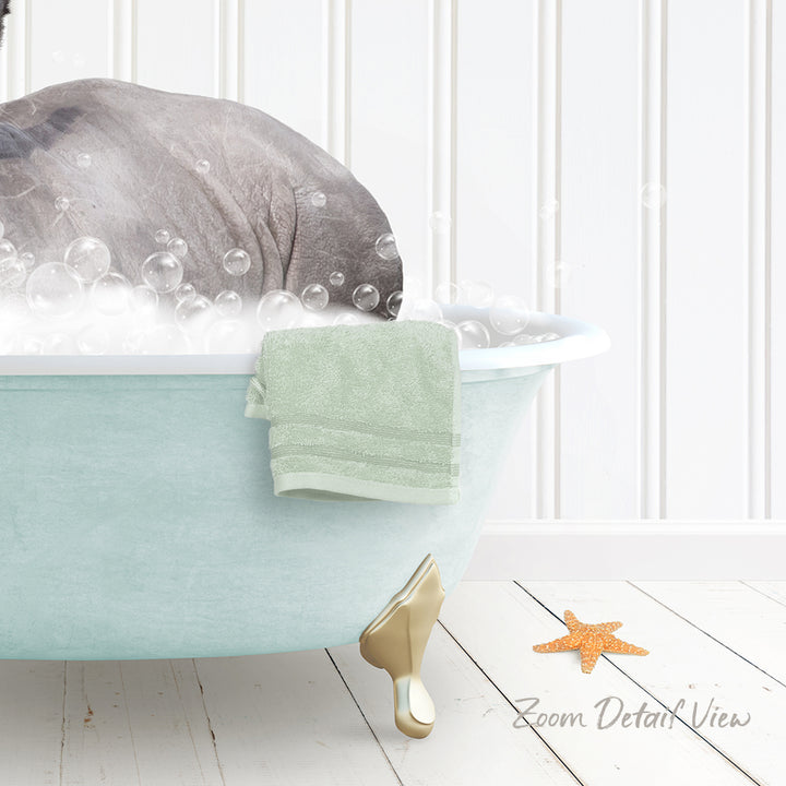 A gray elephant is sitting in a light blue bathtub filled with bubbles, with a green towel hanging on the side and a starfish on the floor next to the tub.