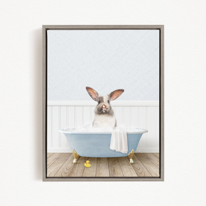 A white rabbit sitting in a blue bathtub filled with water, with a yellow rubber duck nearby.