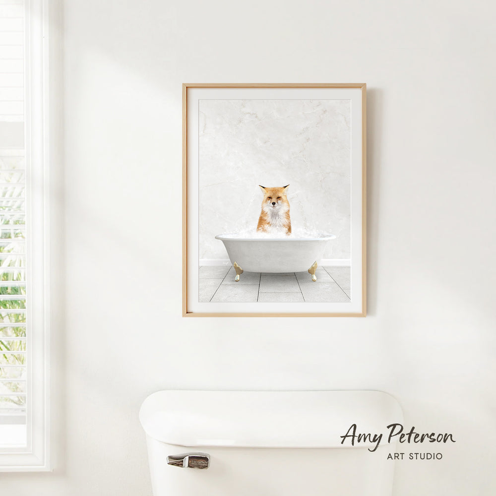 A framed image of a cat sitting in a bathtub, with a white wall and a toilet in the foreground.