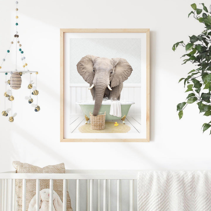 A framed image of an elephant standing in a bathtub, with a basket of yellow objects nearby.