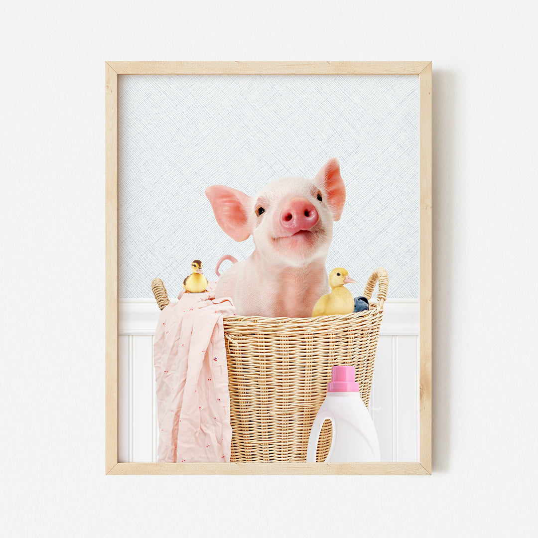 a little pig sitting in a basket with a pink towel