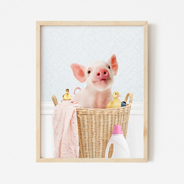 a little pig sitting in a basket with a pink towel