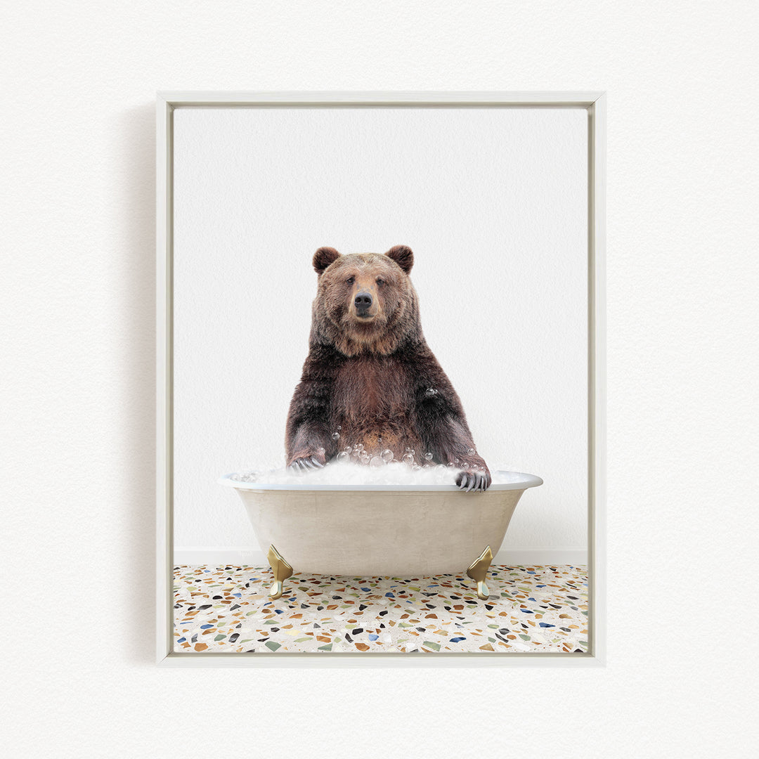 A brown bear sitting in a white bathtub filled with water, with a speckled floor in the background.