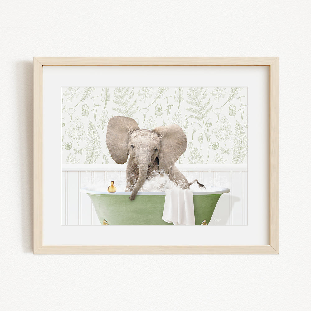 A framed image depicting a baby elephant sitting in a green bathtub, surrounded by a patterned wall and a small toy.