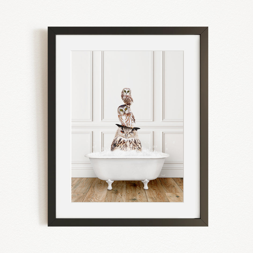 A framed image depicting a white bathtub filled with water, with a stack of owls perched on top of it.