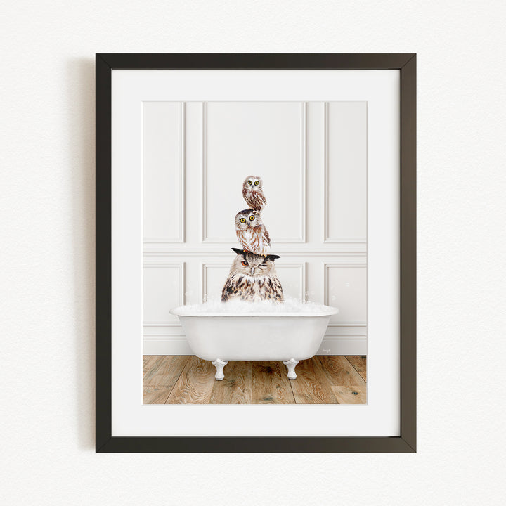 A framed image depicting a white bathtub filled with water, with a stack of owls perched on top of it.