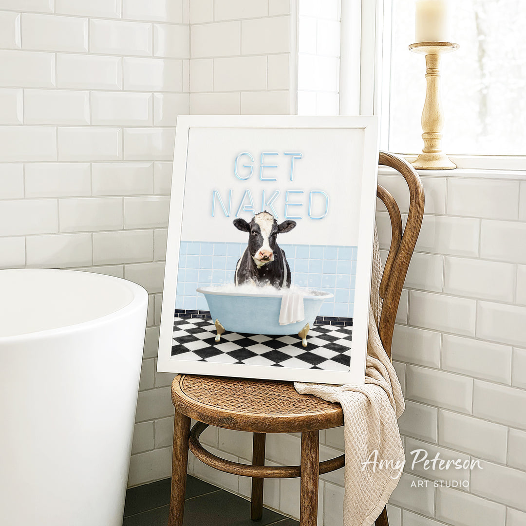 A framed image of a cow sitting in a bathtub, with the text "GET NAKED" displayed on the frame.