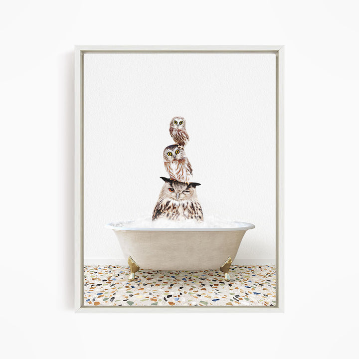 A framed image depicting three owls sitting in a bathtub, with one owl perched on top of the other two.