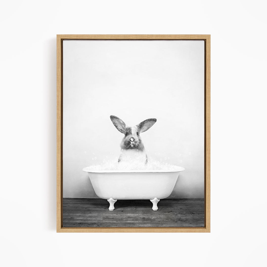 A black and white image of a rabbit sitting in a bathtub filled with water.
