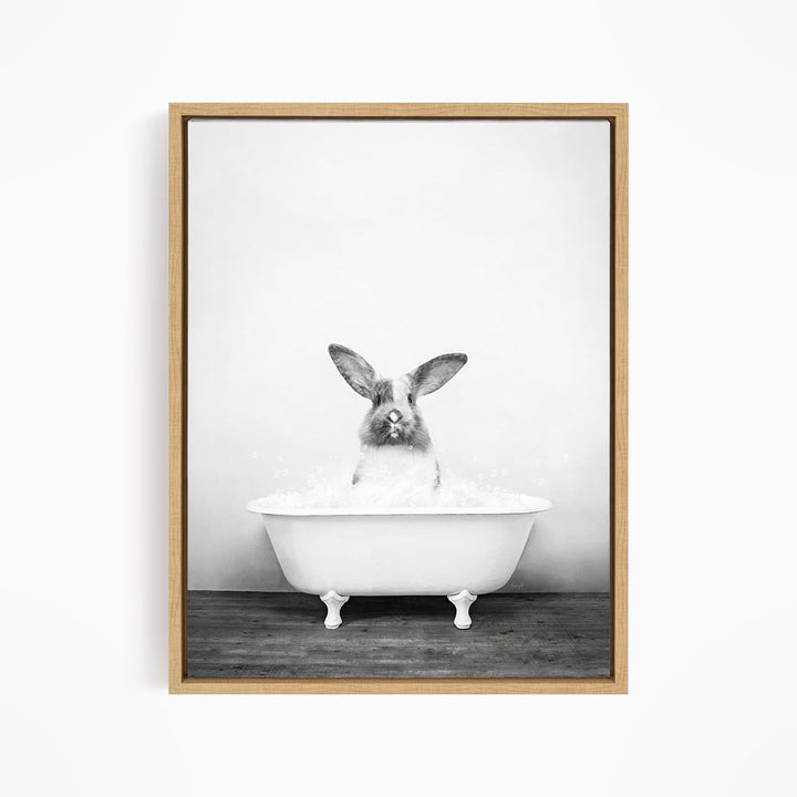 A black and white image of a rabbit sitting in a bathtub filled with water.