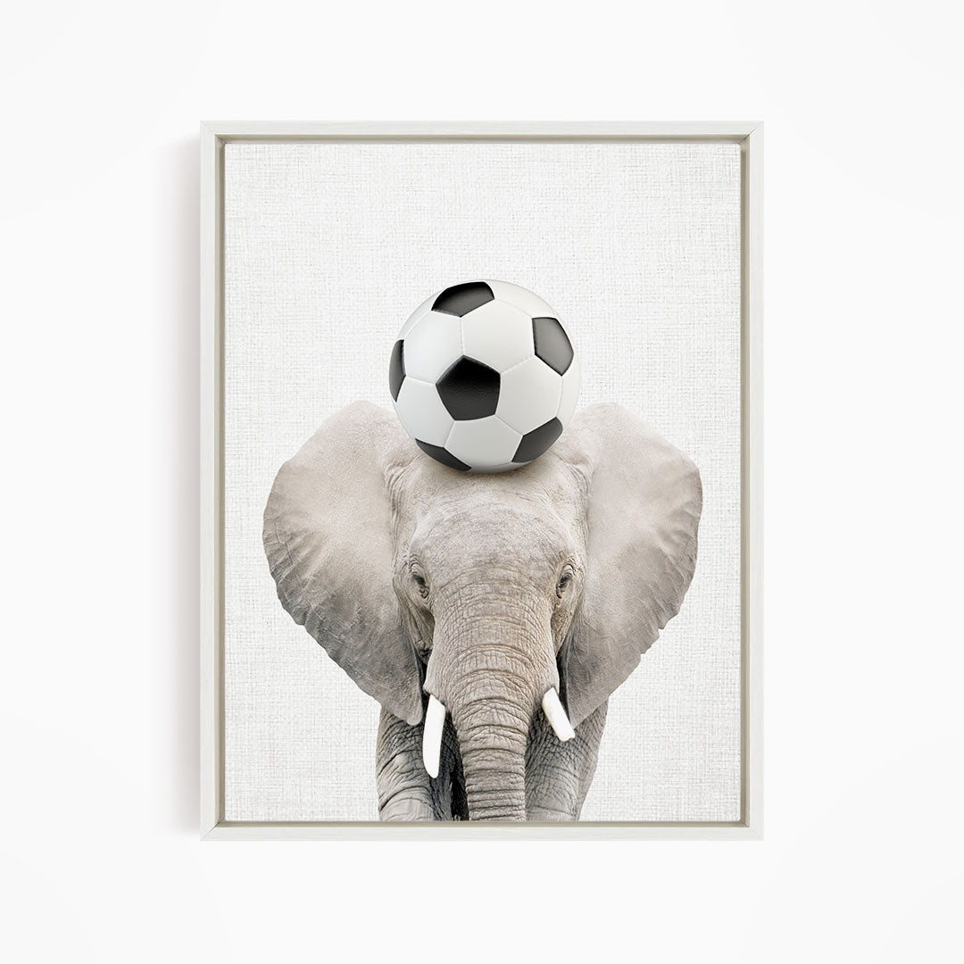 A gray elephant balances a soccer ball on its head.
