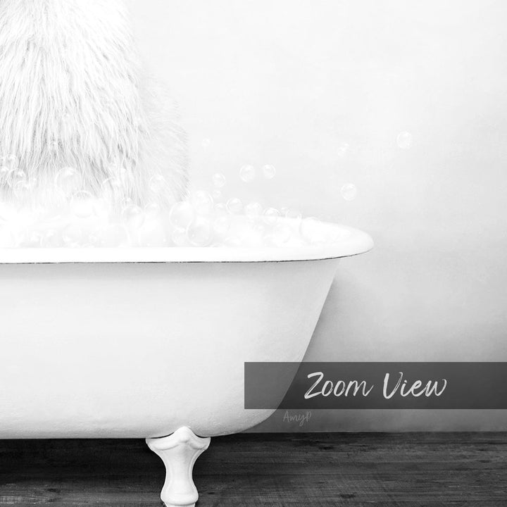A white claw-foot bathtub filled with bubbles, with a fluffy white object sitting on top of the tub.