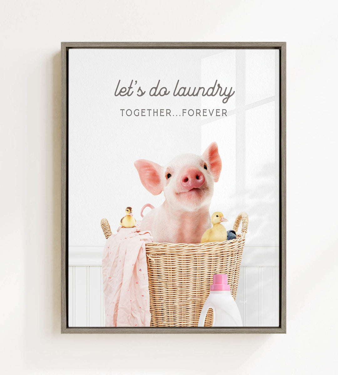A pig sitting in a wicker basket filled with various items, including a bottle of detergent, a yellow duck, and a pink blanket.