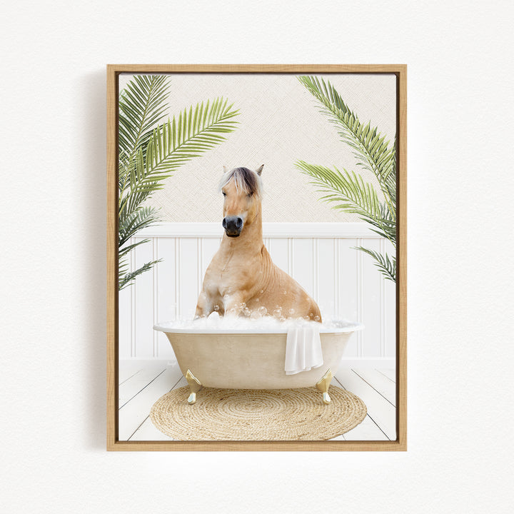 A light brown horse is sitting in a white bathtub filled with bubbles, surrounded by green palm leaves.