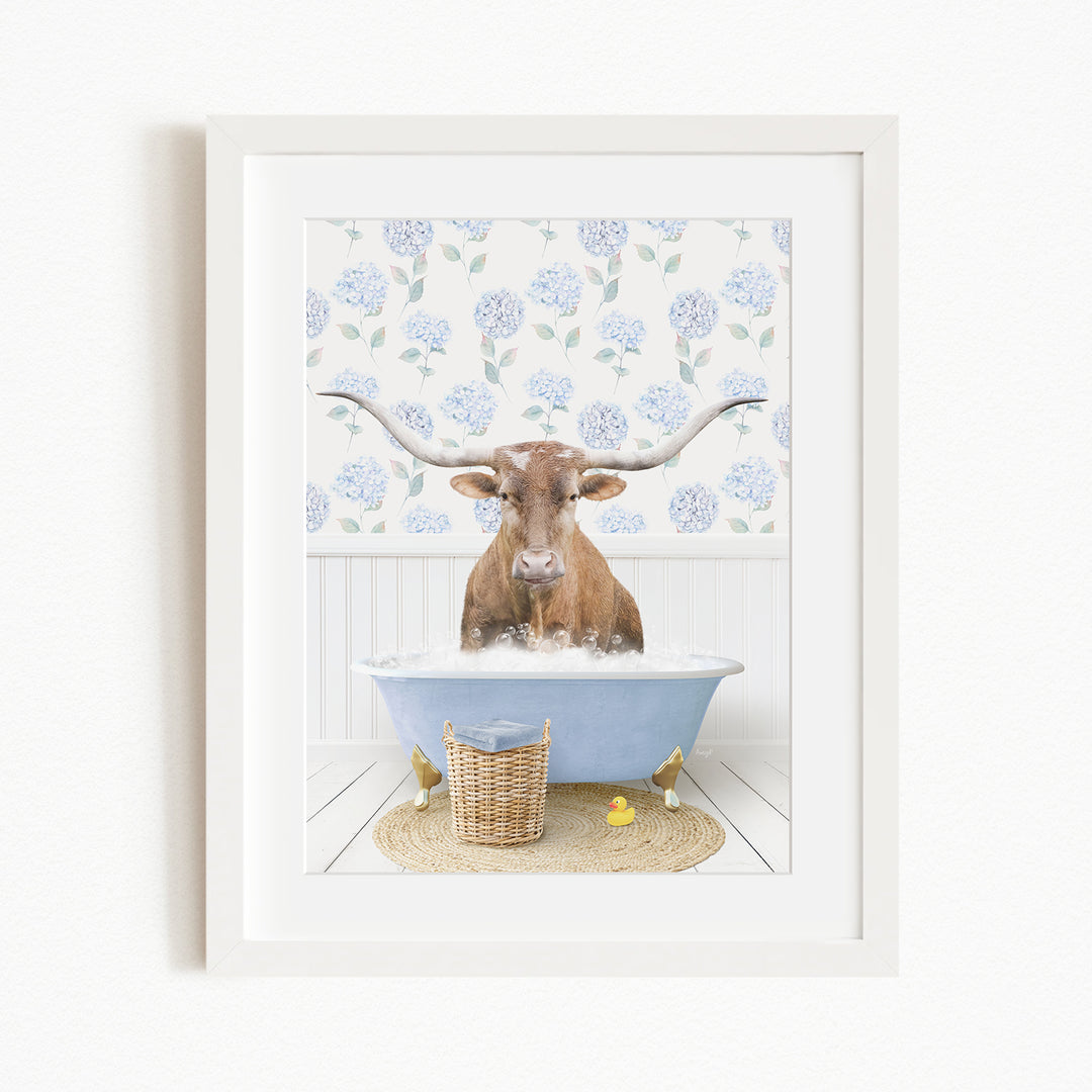 A brown cow with large horns is sitting in a blue bathtub filled with water, surrounded by a white wall with blue floral wallpaper.
