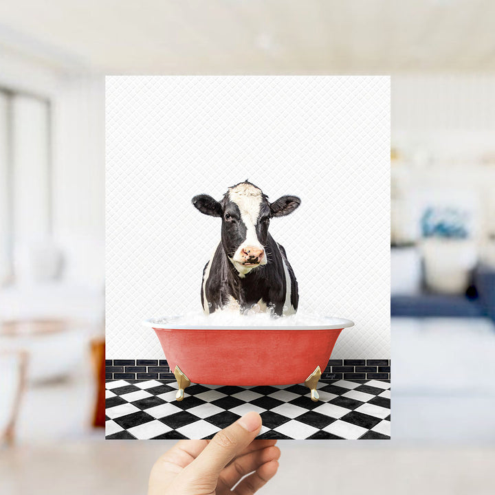 A black and white cow is sitting in a red bathtub filled with water, creating a whimsical and humorous scene.