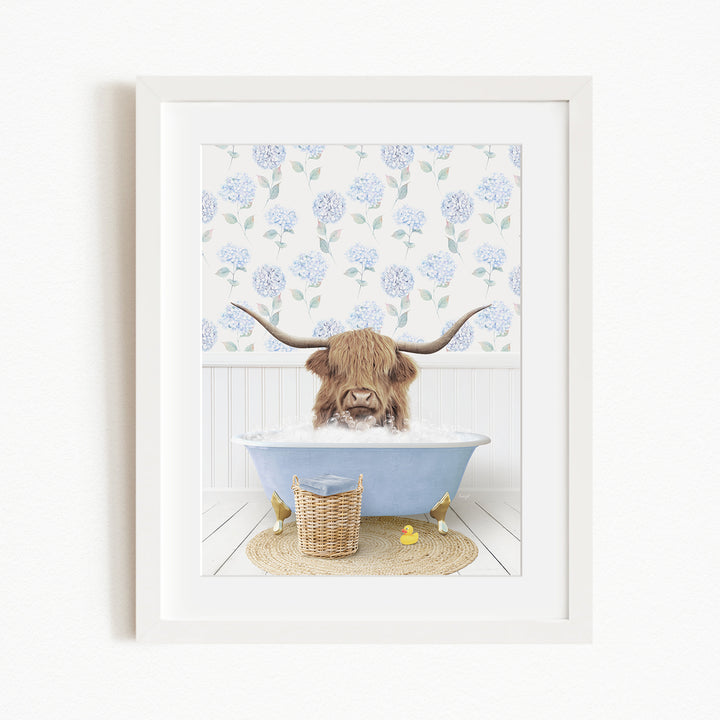 A brown cow with long horns is sitting in a blue bathtub filled with water, surrounded by a white floral wallpaper and a yellow rubber duck.
