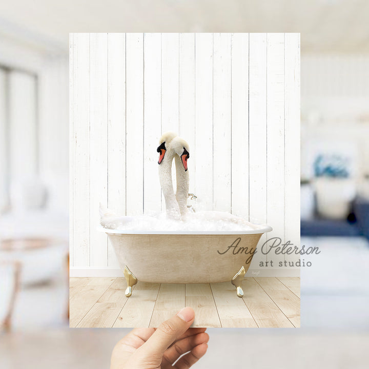 a person holding a picture of two swans in a bathtub