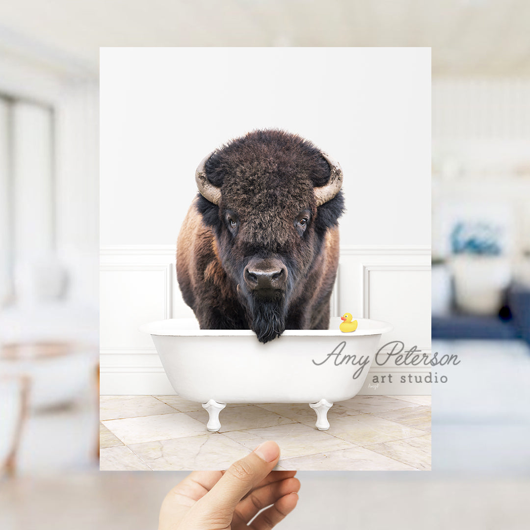 a person holding up a picture of a bison in a bathtub