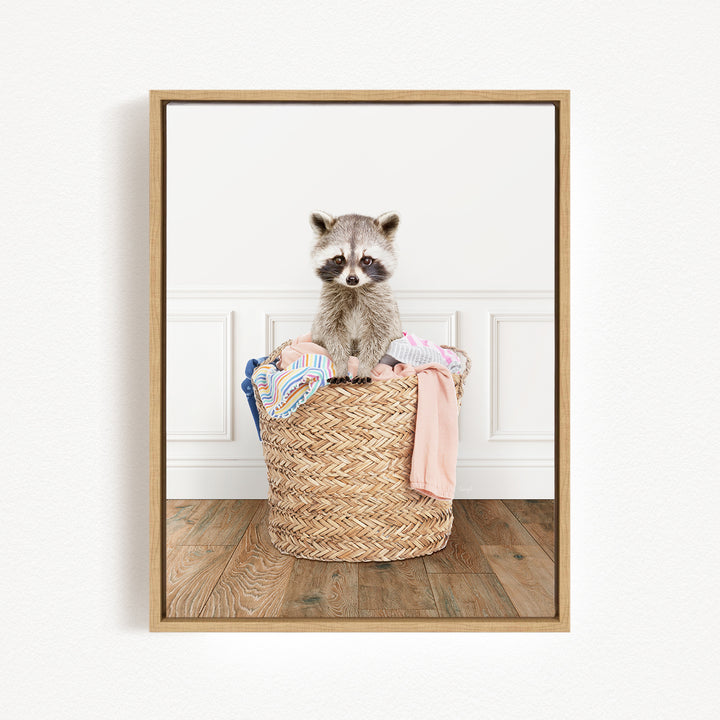 A raccoon sitting in a woven basket filled with clothes.