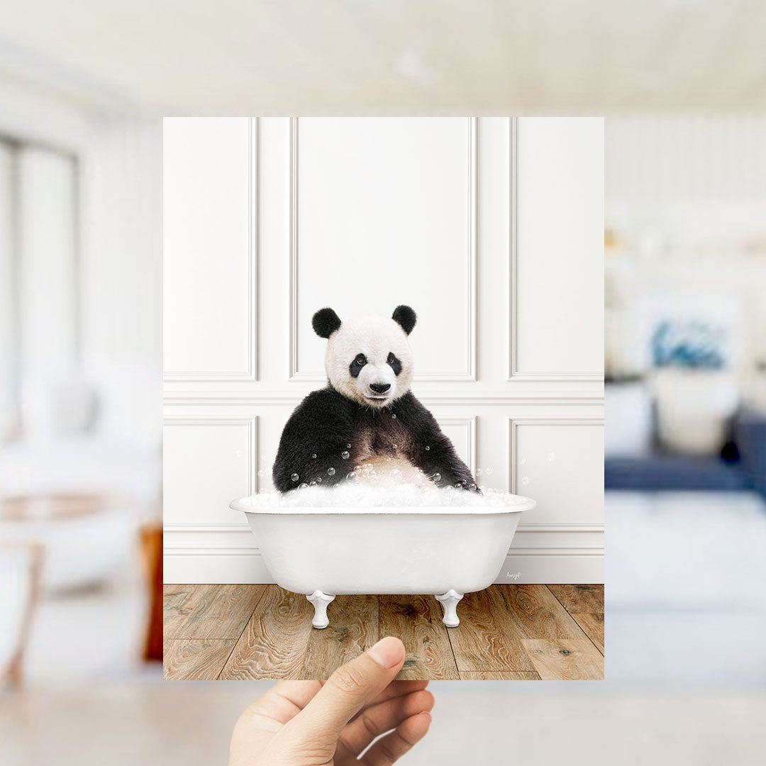 A panda bear sitting in a white bathtub filled with bubbles, with a blurred background suggesting a bathroom setting.
