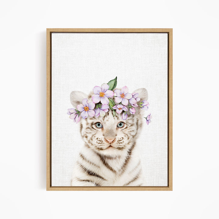 A young tiger cub wearing a floral headpiece, with its eyes looking directly at the camera.