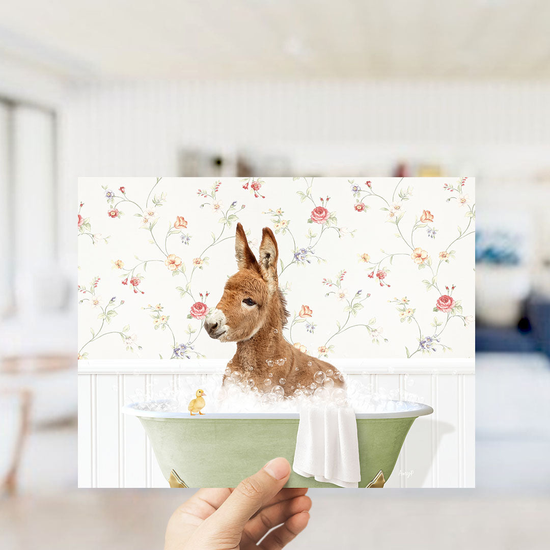 A hand holding a framed image of a kangaroo sitting in a bathtub, surrounded by a floral pattern.