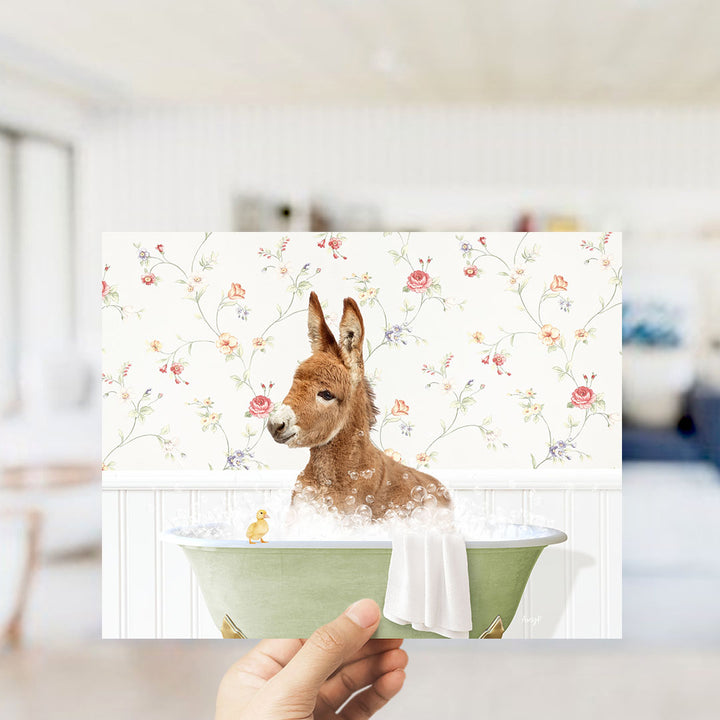 A hand holding a framed image of a kangaroo sitting in a bathtub, surrounded by a floral pattern.
