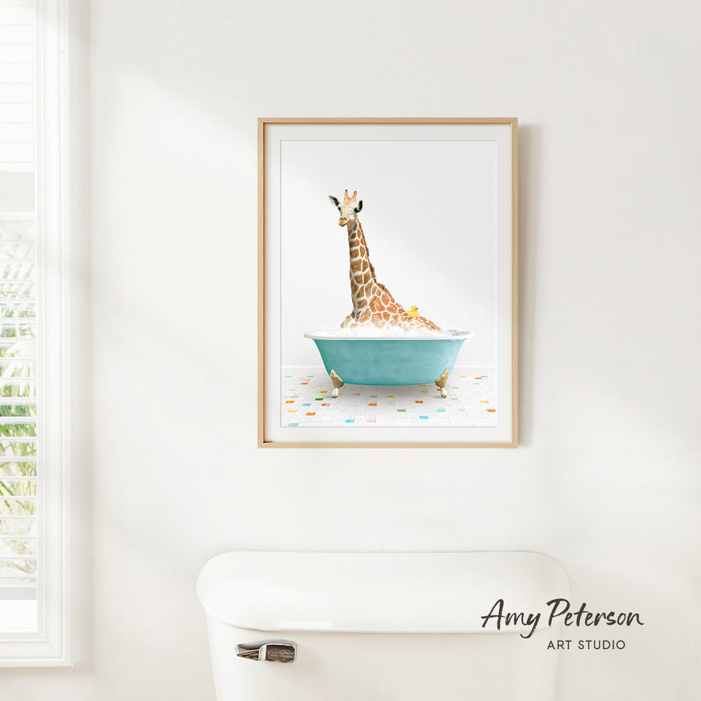 A framed watercolor painting of a giraffe sitting in a blue bathtub, with a white toilet and a window in the background.