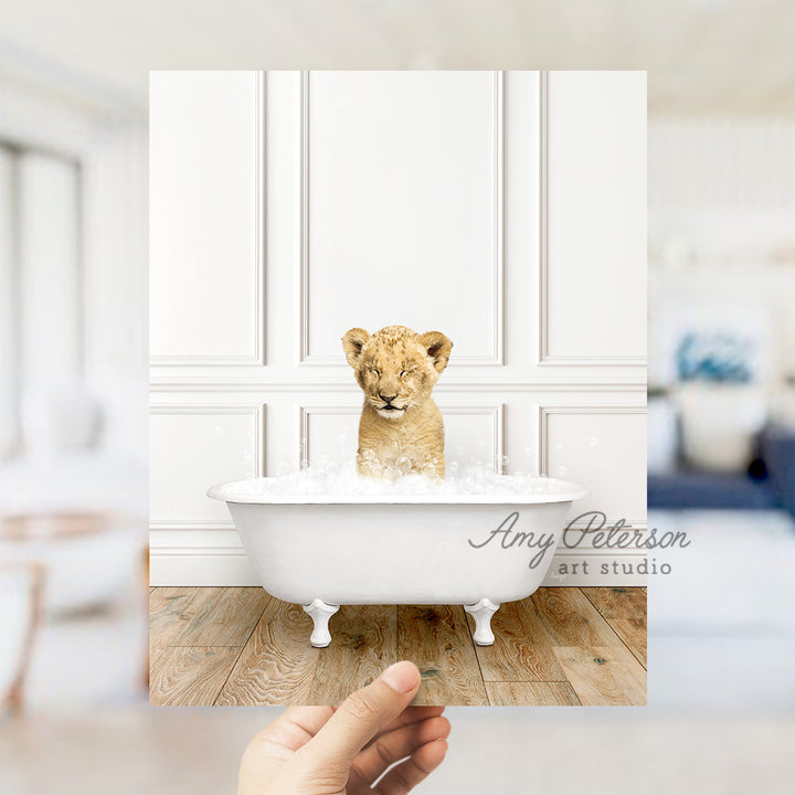 a hand holding a photo of a baby lion in a bathtub