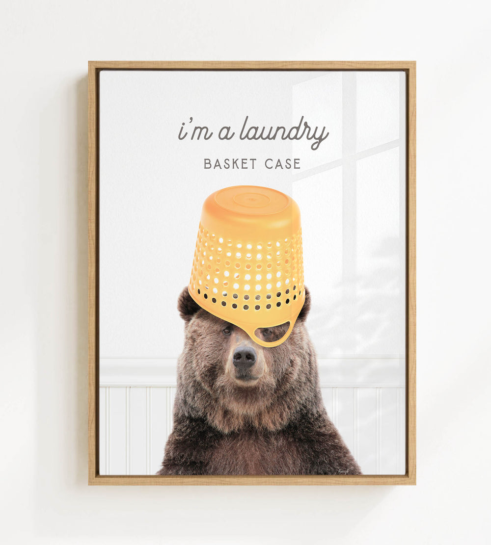 A framed image of a bear wearing a yellow plastic basket on its head, with the text "I'm a laundry basket case" above it.