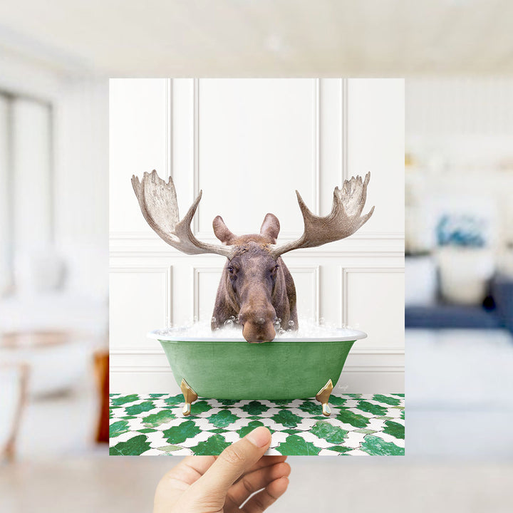 A moose with large antlers is sitting in a green bathtub filled with water, surrounded by a patterned green and white floor.