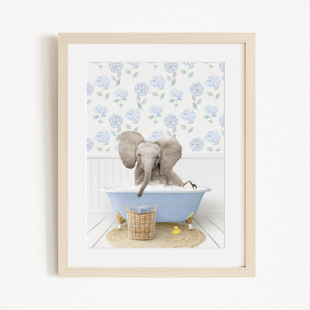 A gray elephant is sitting in a blue bathtub filled with water, surrounded by a floral patterned wall and a basket of rubber ducks.