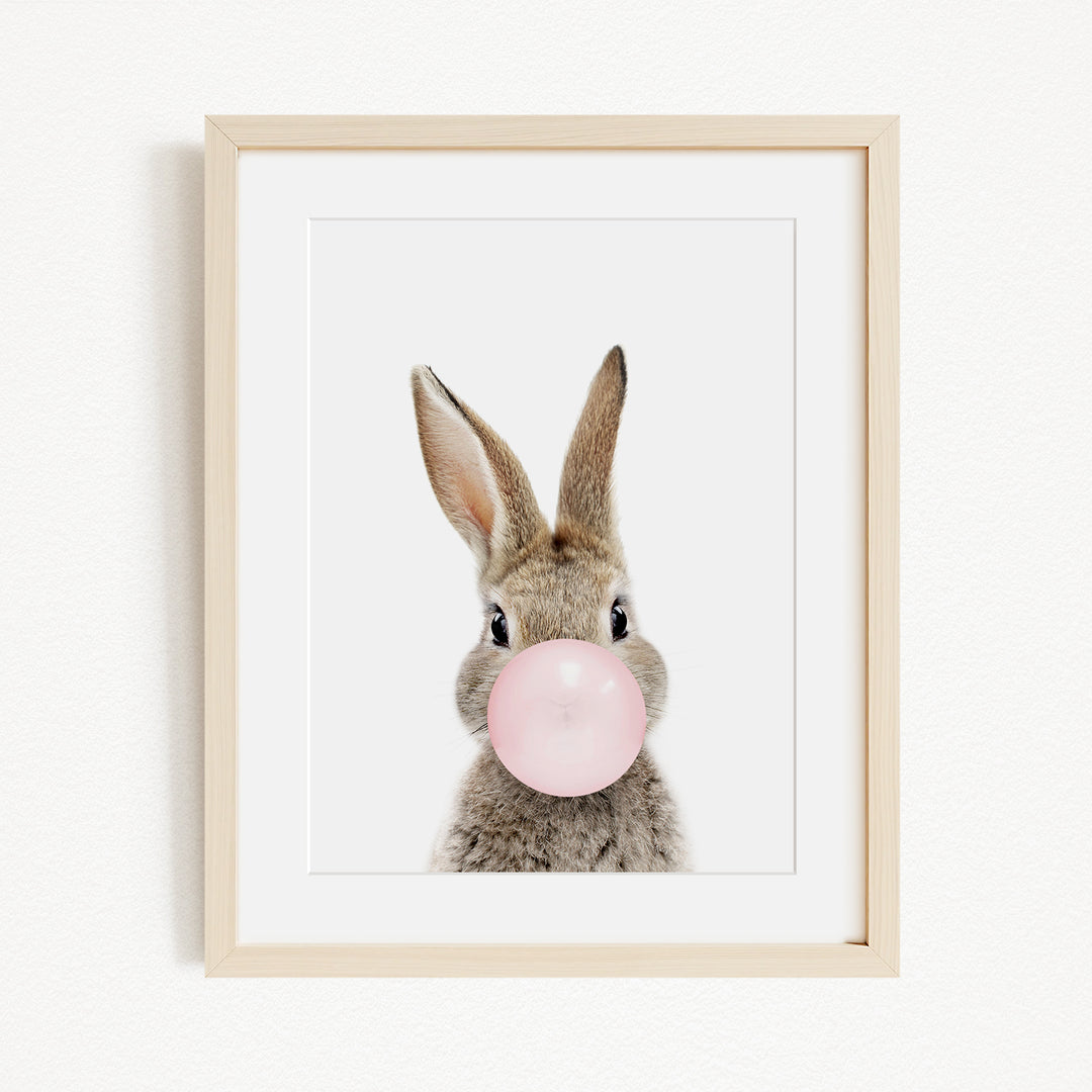 A cute rabbit blowing a pink bubble with its nose.