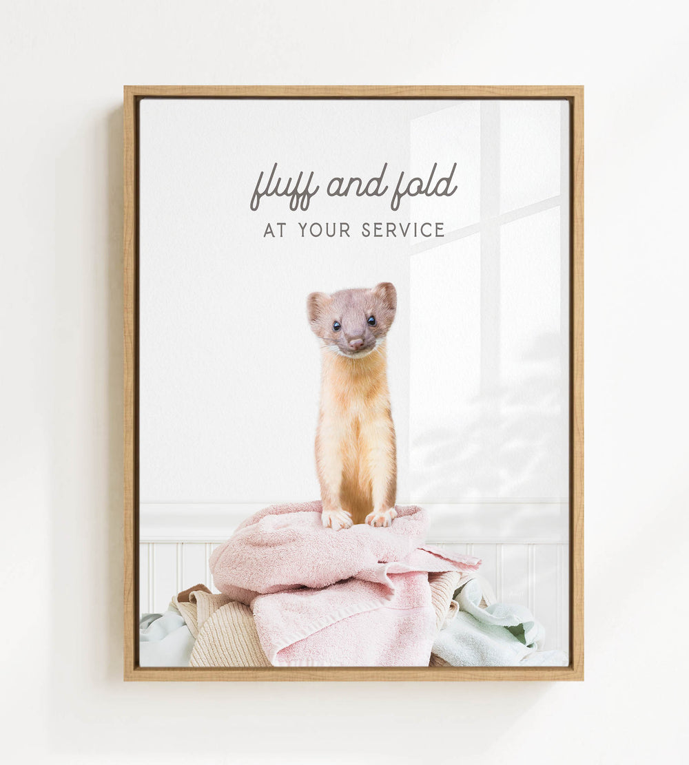 A small brown and white ferret sitting on a pile of clothes, with the text "fluff and fold at your service" written above the image.