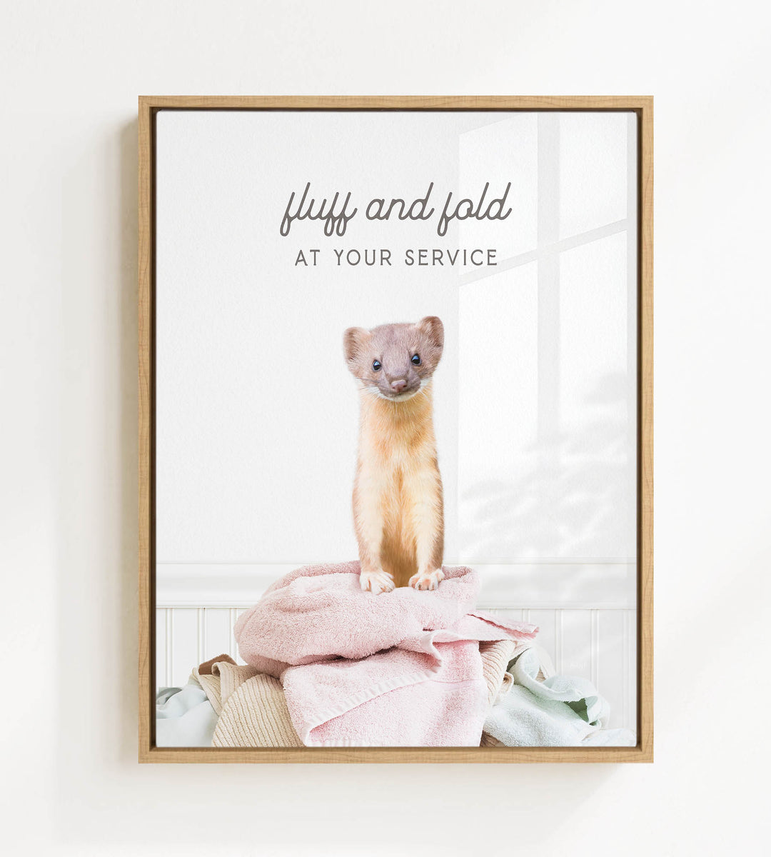 A small brown and white ferret sitting on a pile of clothes, with the text "fluff and fold at your service" written above the image.