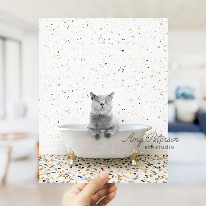 a hand holding a card with a cat sitting in a bathtub