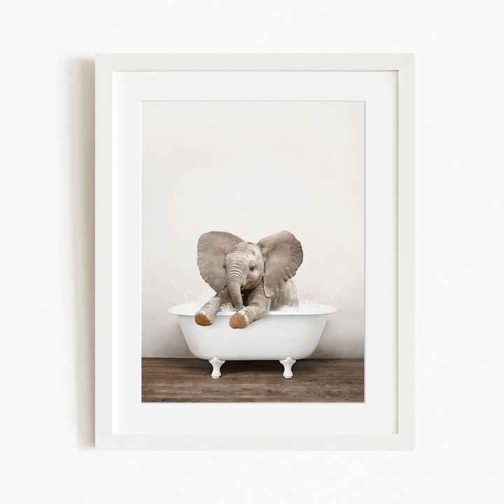 A baby elephant sitting in a white bathtub, with its trunk raised and ears spread out.