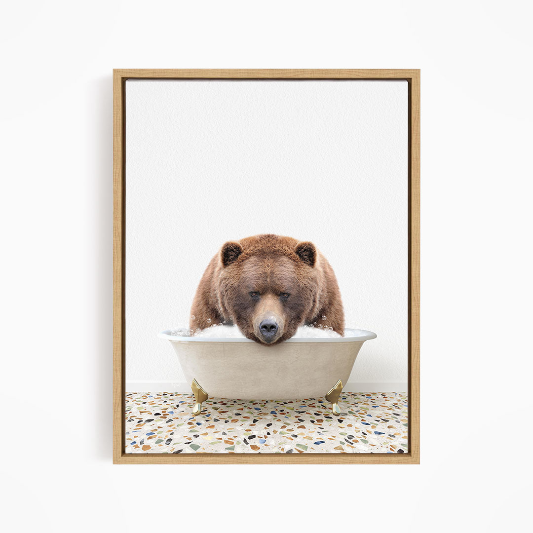 A brown bear is sitting in a white bathtub filled with water, appearing to be enjoying a relaxing bath.