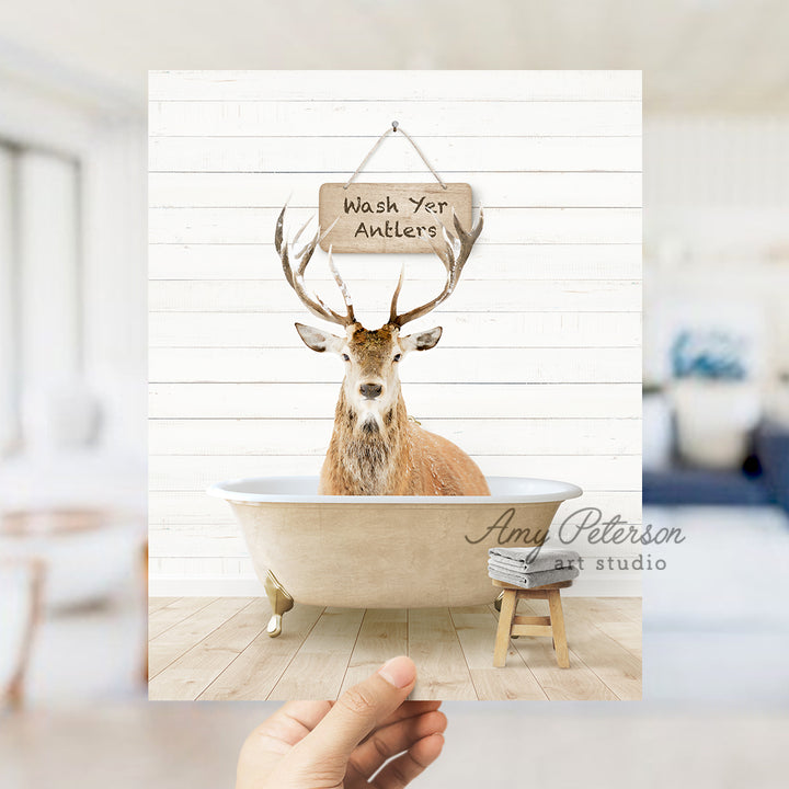 a hand holding up a photo of a deer in a bathtub