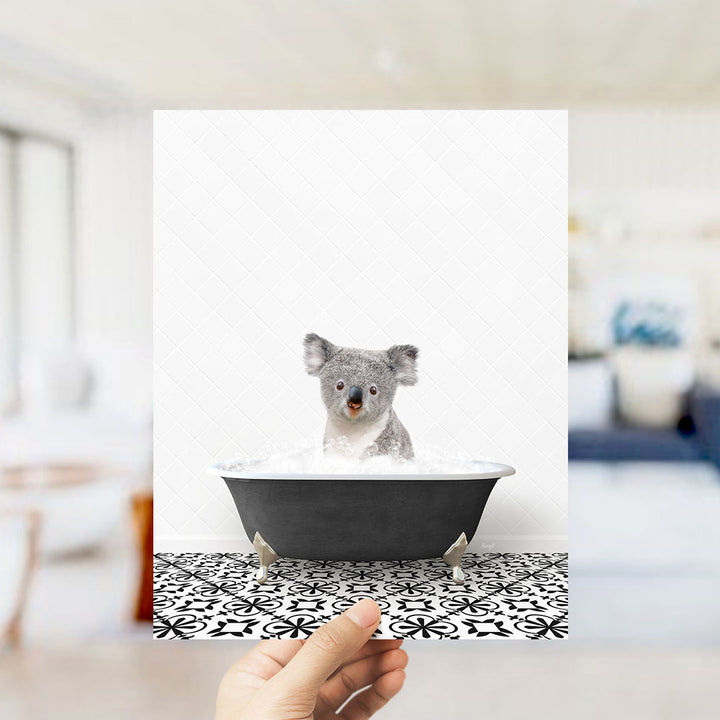 A koala bear sitting in a bathtub filled with water, looking at the camera.