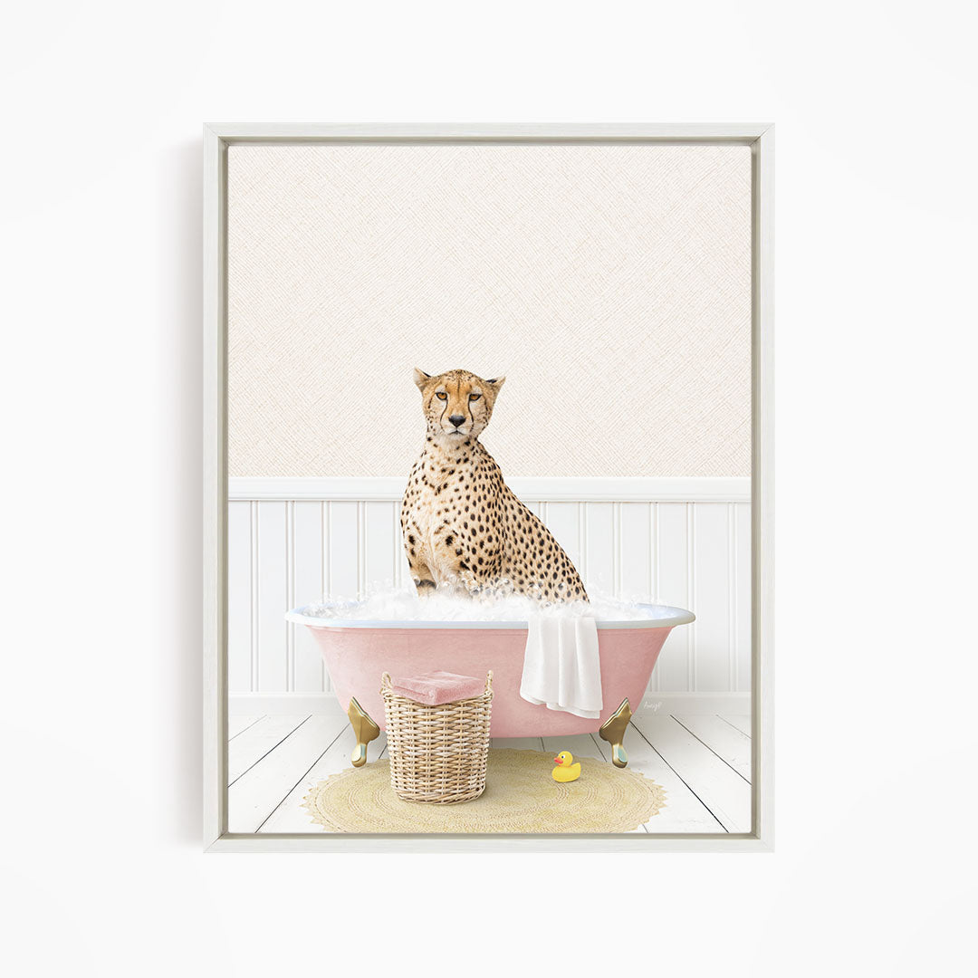 A cheetah sitting in a pink bathtub filled with bubbles, surrounded by a yellow rubber duck and a wicker basket.