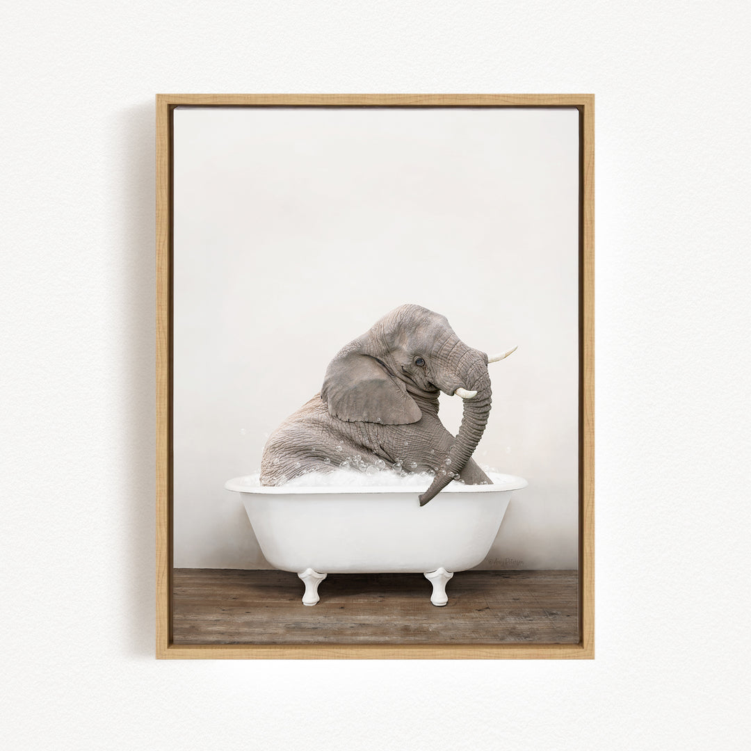 A gray elephant is sitting in a white bathtub, with its trunk raised and appearing to be enjoying the bath.