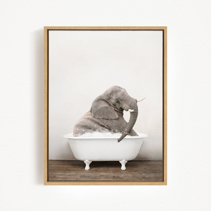 A gray elephant is sitting in a white bathtub, with its trunk raised and appearing to be enjoying the bath.