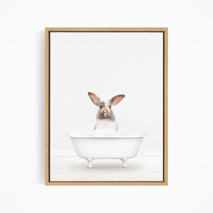 A white rabbit sitting in a white bathtub filled with bubbles, looking directly at the camera.