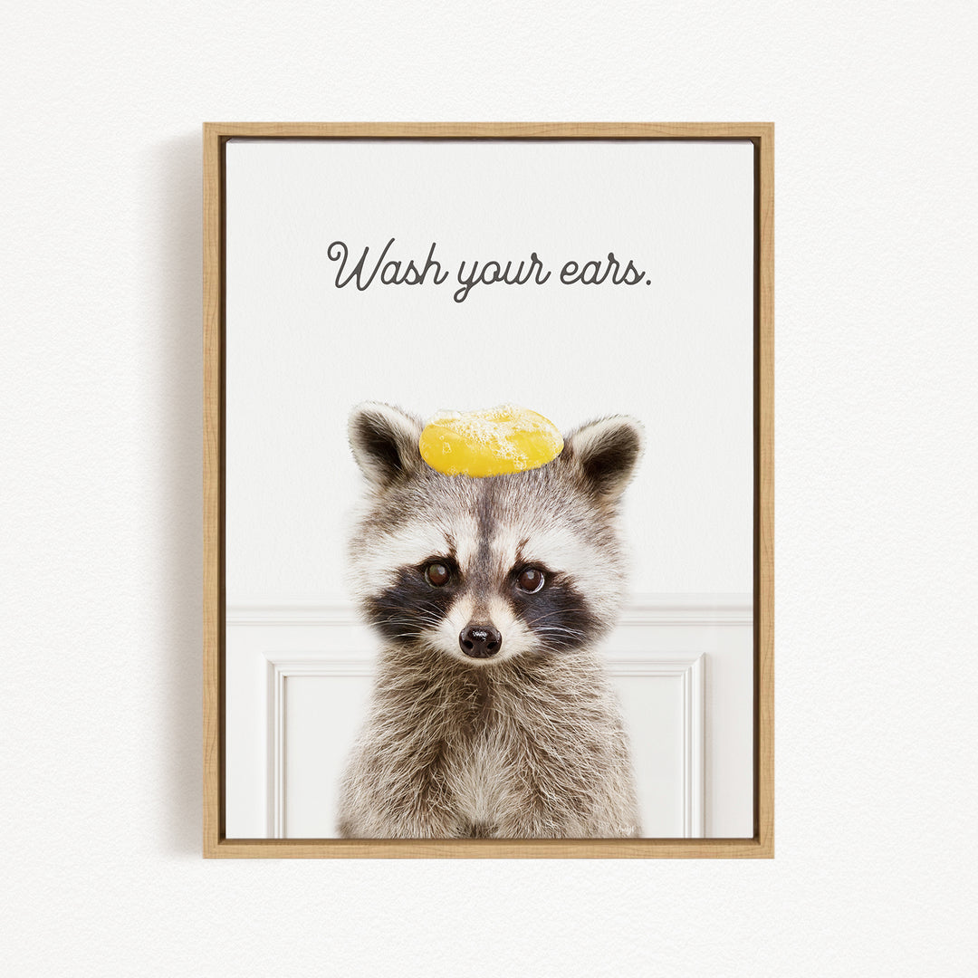 A raccoon wearing a yellow object on its head, with the text "Wash your ears" written above it.