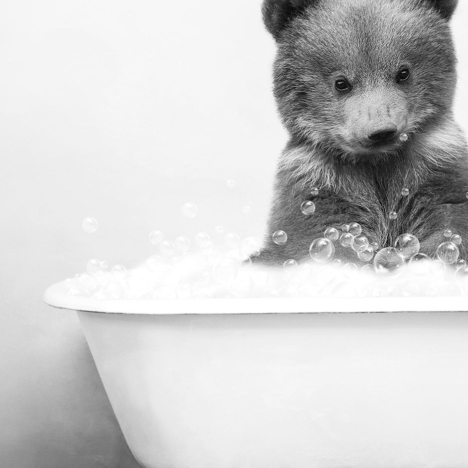 a black and white photo of a baby bear in a bathtub