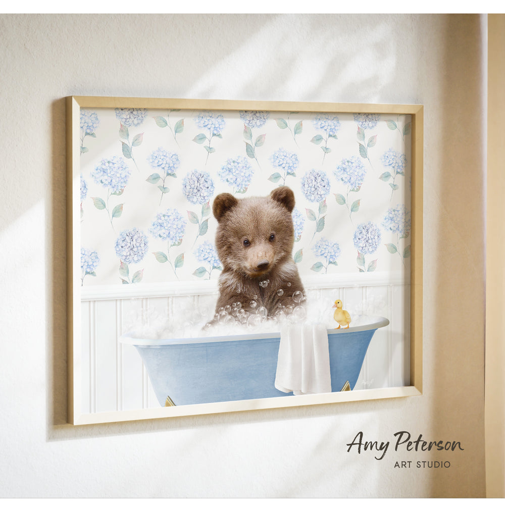 A framed image of a brown bear sitting in a blue bathtub filled with bubbles, with a yellow duck floating nearby.