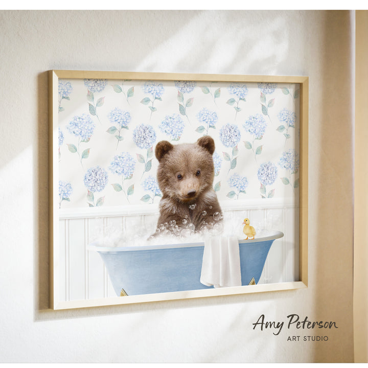 A framed image of a brown bear sitting in a blue bathtub filled with bubbles, with a yellow duck floating nearby.