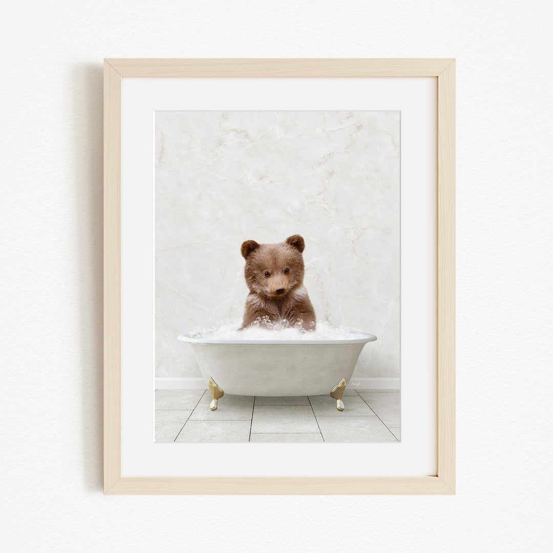 A cute brown bear sitting in a white bathtub filled with bubbles, creating a whimsical and adorable scene.
